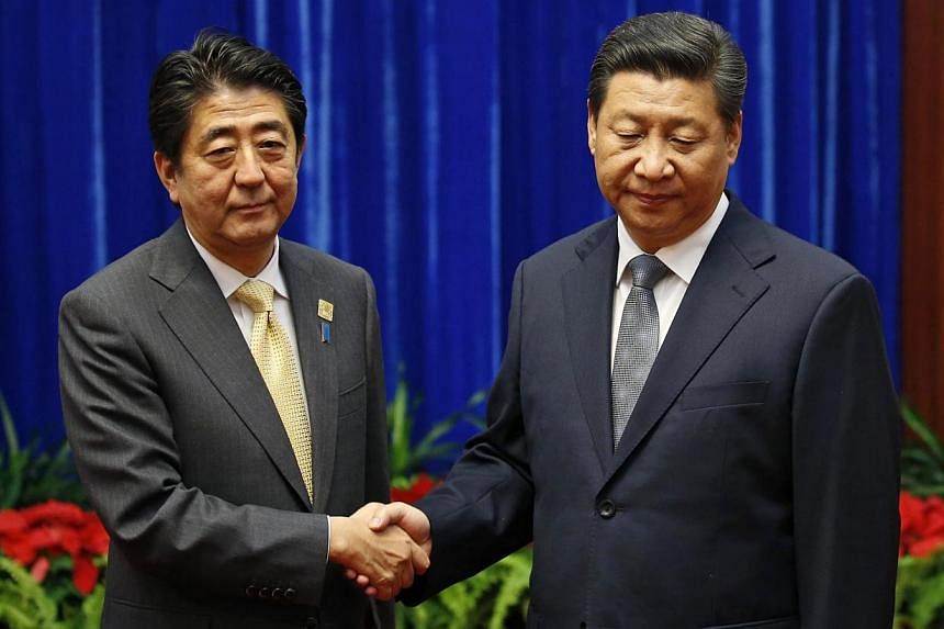 China's President Xi Jinping (right) shakes hands with Japan's Prime Minister Shinzo Abe during their meeting at the Great Hall of the People, on the sidelines of the Asia Pacific Economic Cooperation (APEC) meetings, in Beijing on Nov 10, 2014. -- P