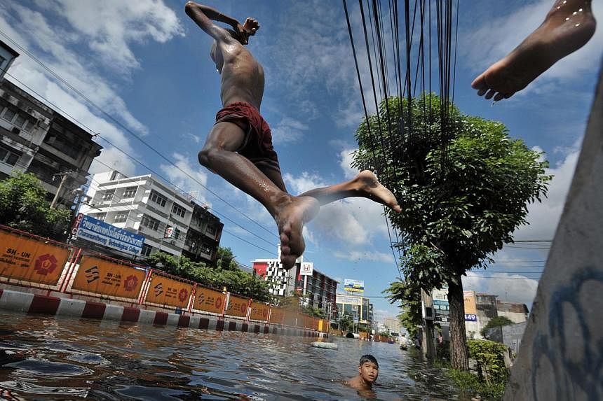 Children playing in a flooded district in Bangkok in October 2011. The Thai state's response to the floods reflected social and spatial injustices, as certain areas and people were protected or compensated more than others.