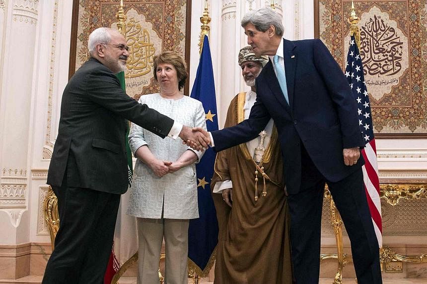 US Secretary of State John Kerry (right) and Iranian Foreign Minister Javad Zarif (left) shake hands as Omani Foreign Minister Yussef bin Alawi (second from right) and EU envoy Catherine Ashton watch in Muscat on Nov 9, 2014. -- PHOTO: REUTERS