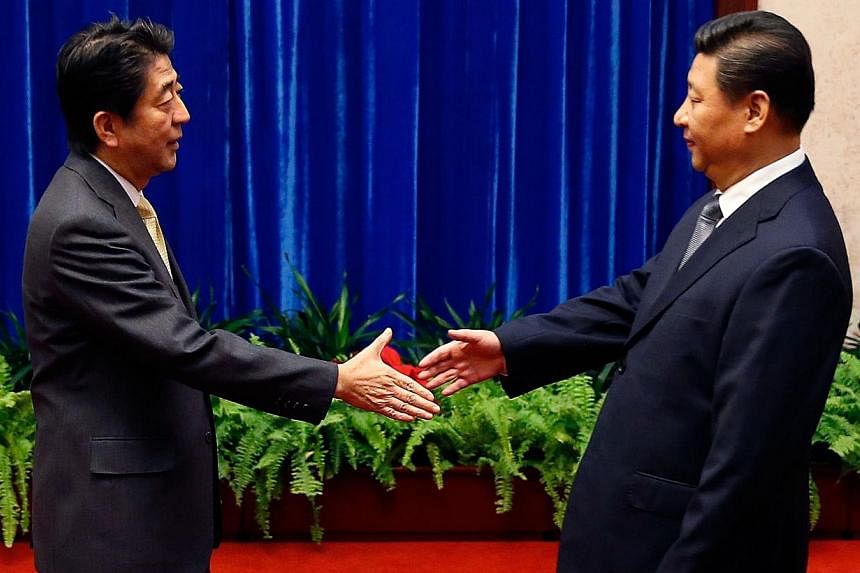 Japan's Prime Minister Shinzo Abe (left) shakes hands with China's President Xi Jinping during their meeting at the Great Hall of the People on the sidelines of the Asia-Pacific Economic Cooperation Summit in Beijing on Nov 10, 2014. -- PHOTO: AFP