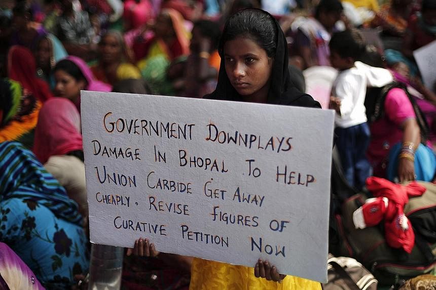 A child of a victim of the Bhopal gas tragedy, a gas leak from a Union Carbide pesticide plant that killed at least 3500 people, holds a placard during a sit-in protest in New Delhi on Nov 14, 2014. Hundreds of the victims held a sit-in protest and f
