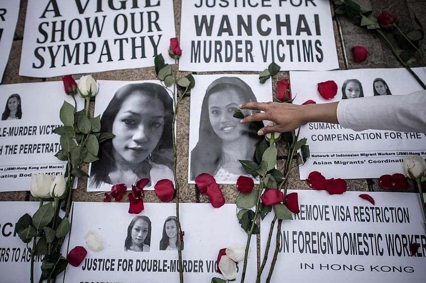 An Indonesian migrant worker lays rose pertals over the pictures of murder victims in Hong Kong on Nov 9, 2014.&nbsp;The bodies of Seneng Mujiasih and Sumarti Ningsih, who were allegedly murdered by a British banker in Hong Kong, have been repatriate