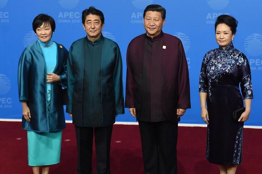 Japan's Prime Minister Shinzo Abe and his wife Akie (left) pose for a photo with Chinese President Xi Jinping and his wife Peng Liyuan as they arrive for the Asia-Pacific Economic Cooperation (APEC) Summit banquet at the National Aquatics Center in t