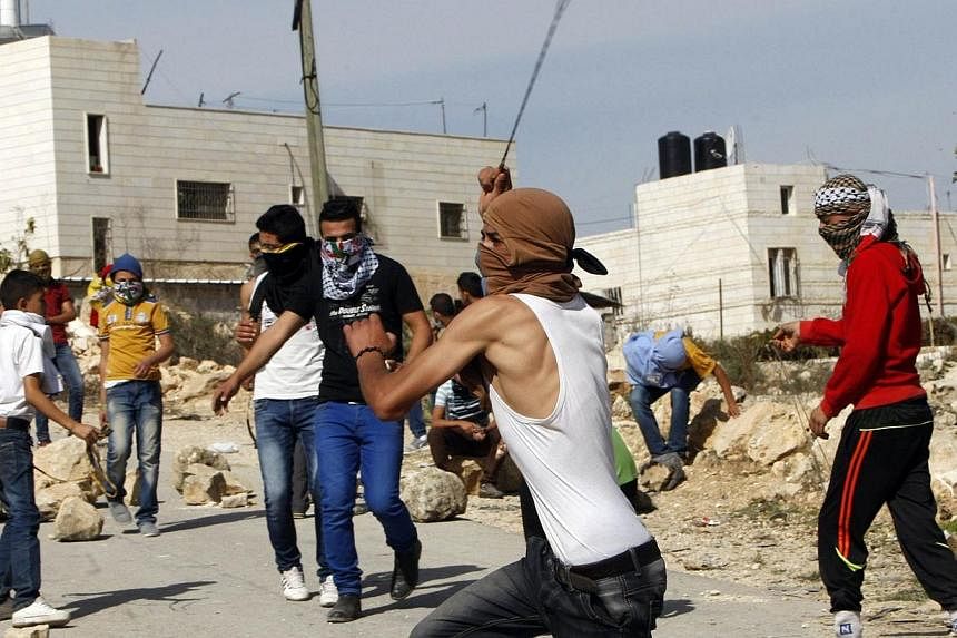 A Palestinian uses a slingshot to throw stones toward Israeli soldiers during clashes in Siear town near the West Bank city of Hebron on Nov 11, 2014.&nbsp;Israeli troops shot dead a Palestinian during clashes on Tuesday in the occupied West Bank, a 