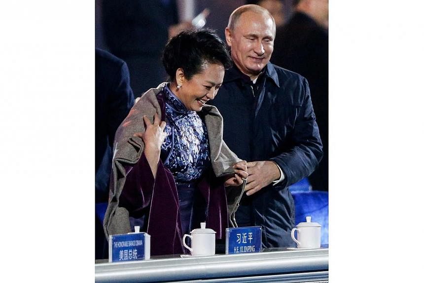 Russia's President Vladimir Putin (right) helps put a blanket on Peng Liyuan, wife of China's President Xi Jinping, as they watch a lights and fireworks show to celebrate Asia-Pacific Economic Cooperation (APEC) Leaders' Meeting, at National Aquatics