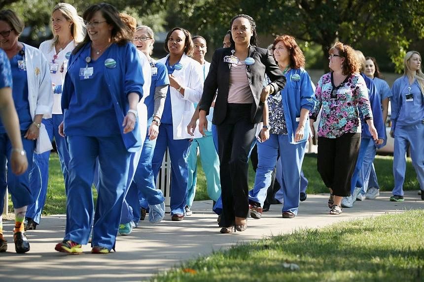 Several dozen nurses from Texas Health Presbyterian Hospital, where Mr Thomas Eric Duncan was treated, gathered in front of the hospital to show support for their employer on Oct 20, 2014 in Dallas, Texas. -- PHOTO: AFP