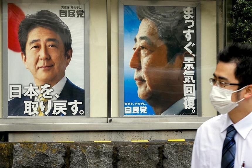 A man walks past posters of Japanese Prime Minister Shinzo Abe outside the headquarters of his Liberal Democratic Party (LDP) in Tokyo on Nov 12, 2014. Mr&nbsp;Abe could call a snap election for next month, two years early, with a plan to boost his s