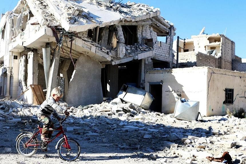 A Syrian boy rides his bike past a destroyed building in the northern Syrian city of Aleppo on Nov 5, 2014.&nbsp;-- PHOTO: AFP
