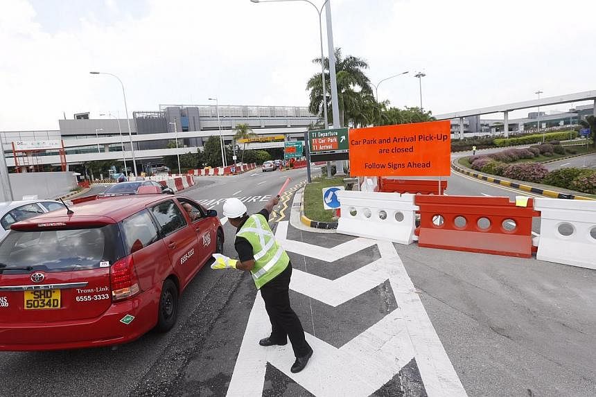 A marshall directing traffic to the new carpark as well as the new T1 arrival pick-up at the closed road of the old T1 carpark on November 12, 2014.&nbsp;-- ST PHOTO: KEVIN LIM