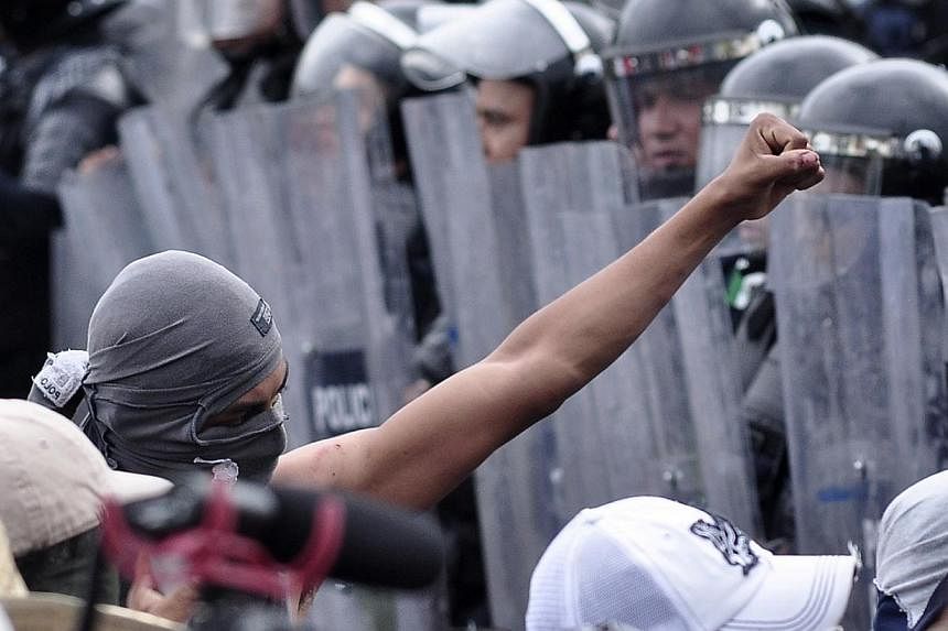 A masked protester shows a fist to a formation of police officers during a protest in reprisal for the alleged killing of 43 students, in Acapulco Nov 10, 2014.&nbsp;Protesters angry at the alleged massacre of 43 Mexican students torched the ruling p