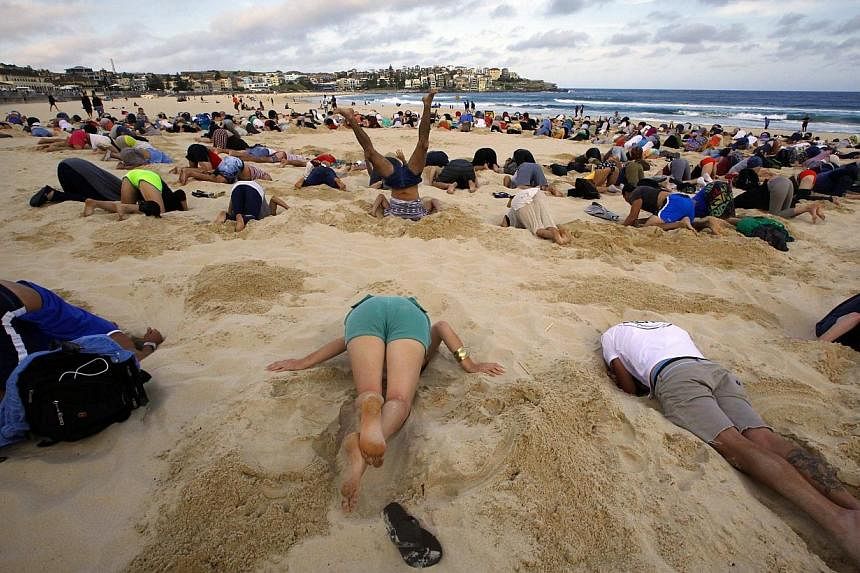 &nbsp;A group of around 400 demonstrators participate in a protest by burying their heads in the sand at Sydney's Bondi Beach on Nov 13, 2014.&nbsp;Scores of Australians buried their heads in the sands of iconic Bondi Beach on Thursday to send a mess