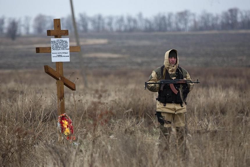 A pro-Russian gunman stands guard as Dutch investigators (unseen) arrive near parts of the Malaysia Airlines Flight MH17 at the crash site near the Grabove village in eastern Ukraine on Nov 11 2014. -- PHOTO: AFP