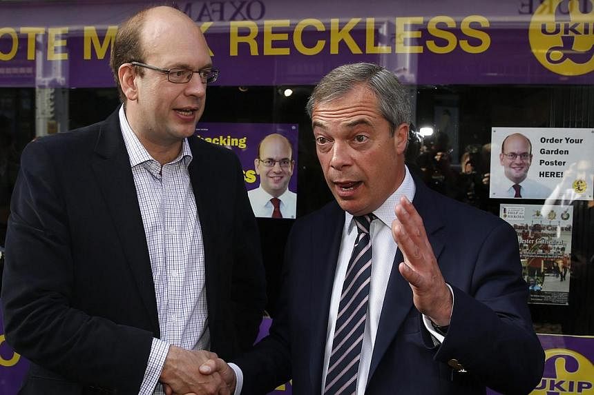 United Kingdom Independence Party (UKIP) leader Nigel Farage (right) reacts during a photocall with former Conservative MP and UKIP candidate Mark Reckless outside the party campaign office in Rochester, south-east England, Oct 11, 2014. -- PHOTO: RE