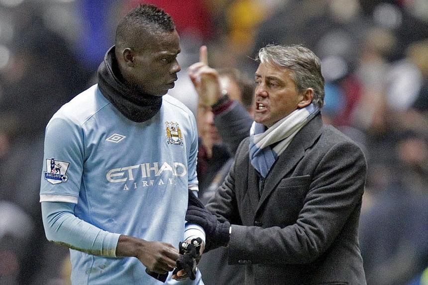 Manchester City's Italian manager Roberto Mancini (right) pushes Italian striker Mario Balotelli back onto the pitch after their 3-1 win in the English Premier League football match against Newcastle United at St James' Park, Newcastle-Upon-Tyne, nor