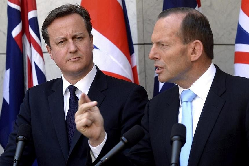 British Prime Minister David Cameron (left) listens to Australian Prime Minister Tony Abbott during a news conference at Parliament House in Canberra on Nov 14, 2014. -- PHOTO: REUTERS
