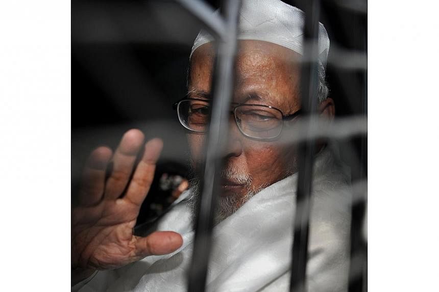 In this file photograph taken on June 16, 2011, radical Indonesian cleric Abu Bakar Bashir waves from a prison van after he was sentenced to 15 years by the court in Jakarta for terrorism charges.&nbsp;Indonesian police and prison authorities denied 