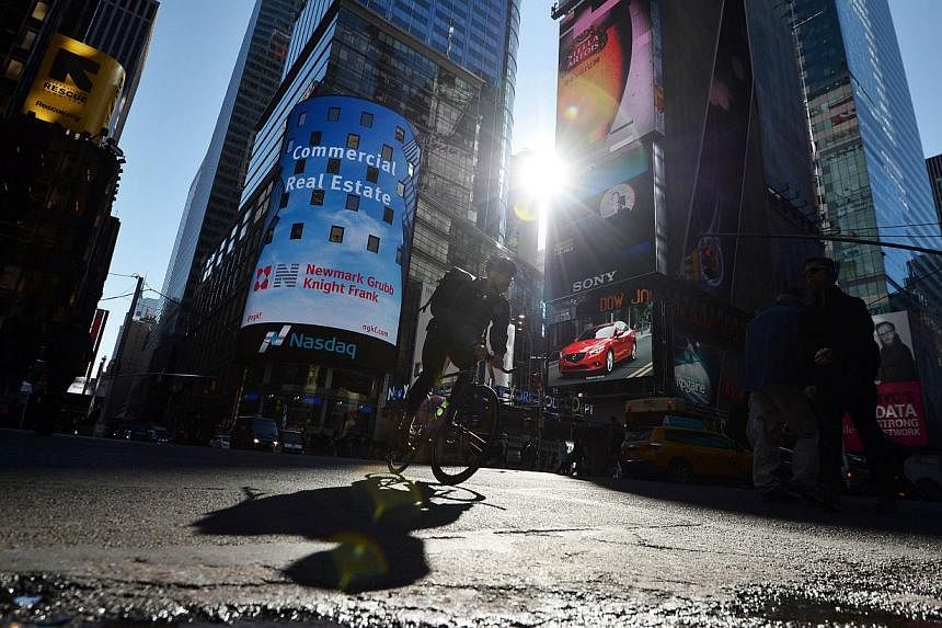 A man rides his bike through Times Square as electronic billboards advertising various products flash around him in New York on Nov 3, 2014. -- PHOTO: AFP