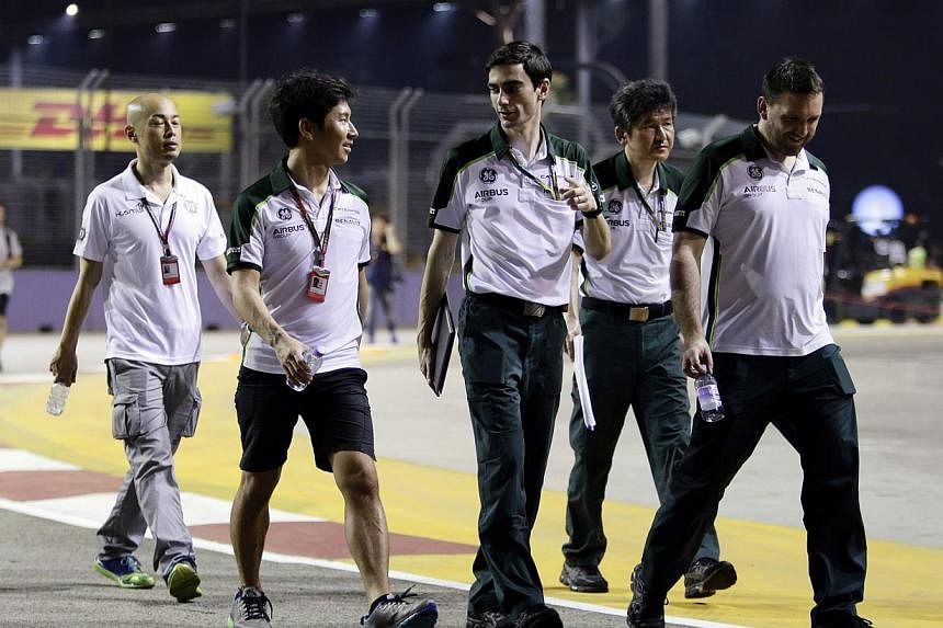 Caterham Formula One driver Kamui Kobayashi (second left) of Japan and crew members walk on the the Marina Bay street circuit ahead of the Singapore F1 Grand Prix in Singapore Sept 18, 2014. The struggling Caterham team are set to return to action in