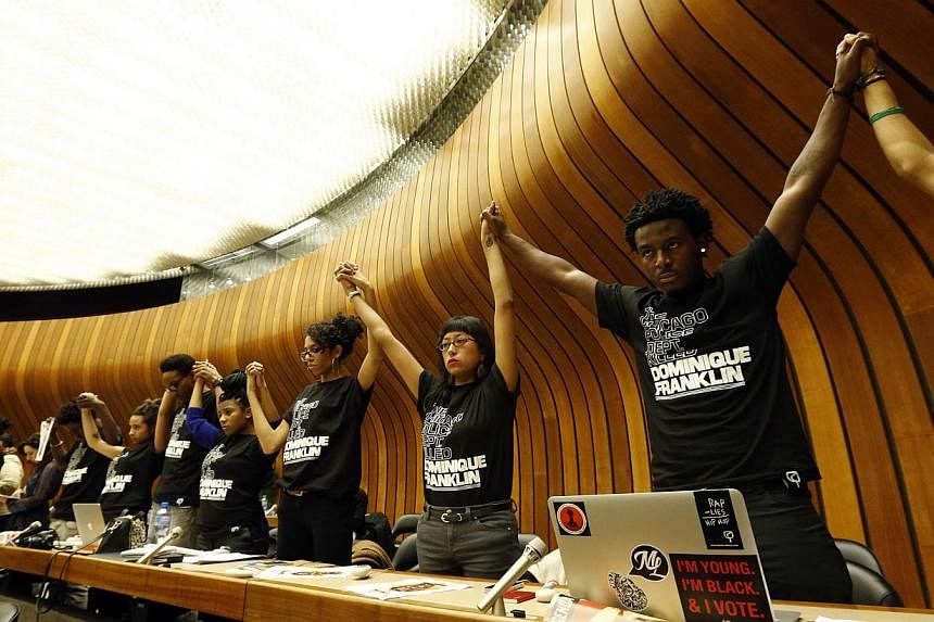 Activists hold hands during a silent protest at a hearing of the United States at the Committee against Torture at the United Nations in Geneva Nov 13, 2014. The activists wore T-shirts with the slogan: "The Chicago Police Dept killed Dominique Frank