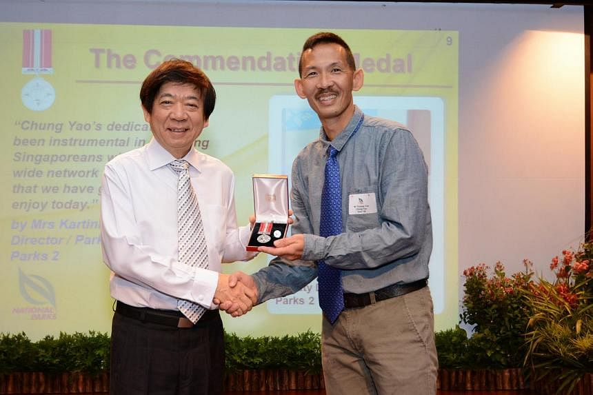 National Development Minister Khaw Boon Wan (left) presenting commendation medal to National Parks Board officer Thomas Yee Chung Yao at the ministry's National Day Awards investiture on Friday, Nov 11, 2014 at MND Auditorium at Maxwell Road. -- PHOT