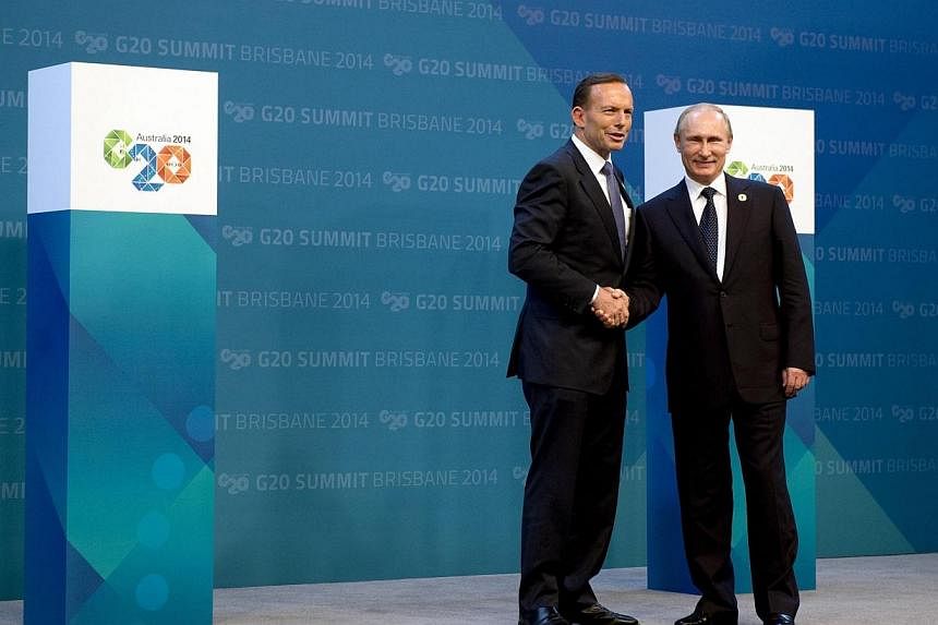 Russia's President Vladimir Putin (right) is welcomed by Australia's Prime Minister Tony Abbott upon his arrival for the G20 summit in Brisbane on Nov 15, 2014. -- PHOTO: REUTERS