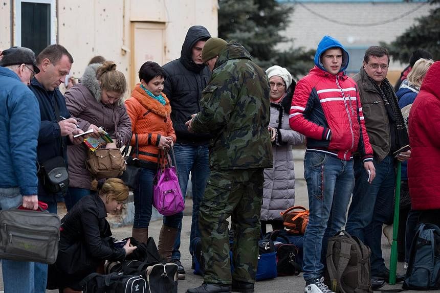 Border guards of the self-declared Donetsk People's Republic check passengers' IDs as they wait to cross from East Ukraine into Russia at the border crossing of Uspenka, on Nov 15 2014. Ukraine's President Petro Poroshenko issued a decree ordering th