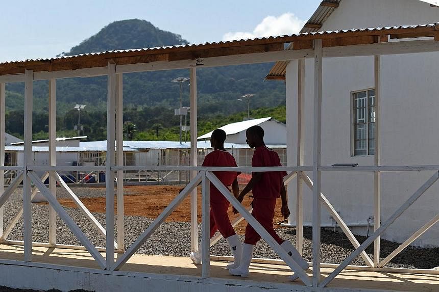 Health workers walk on Nov 13, 2014, on Kerry Town treatment centre, on the outskirts of Freetown, one of several installations built by the British government in Sierra Leone on a effort to fight the outbreak of Ebola. &nbsp;-- PHOTO: AFP