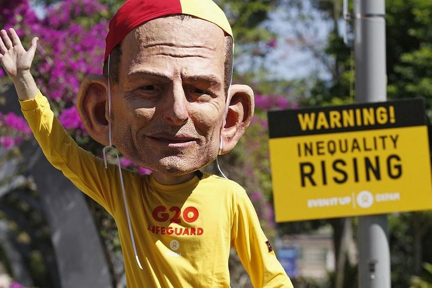 A protester, wearing a mask depicting Australian Prime Minister Tony Abbott, calls for global equality among nations outside the venue site of the annual Group of 20 leaders summit in Brisbane, Nov 14, 2014. G-20 leaders representing the bulk of the 