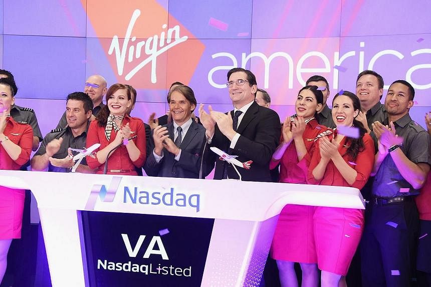 Virgin America president and CEO David Cush (centre) and Nasdaq CEO Robert Greifeld (right) ring the opening bell in celebration of the company's initial public offering on Nov 14, 2014 in New York City. -- PHOTO: AFP