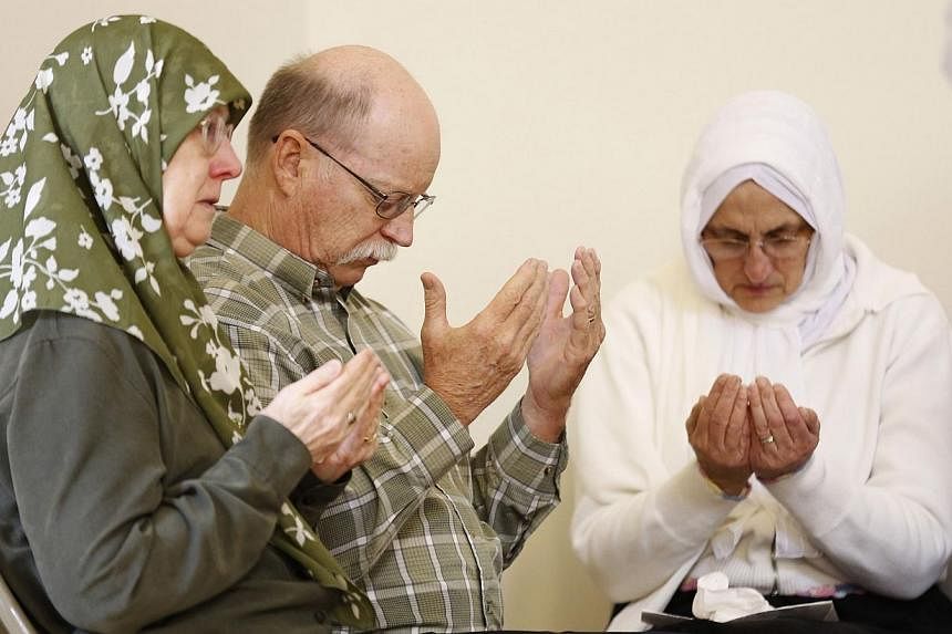 Ed Kassig, along with Habibe Ali (right) and Paula Kassig, pray for his captive son Abdul-Rahman Kassig during a prayer service honouring his humanitarian work in Syria at the Islamic Society of North America mosque in Plainfield, Indiana on Oct 10, 