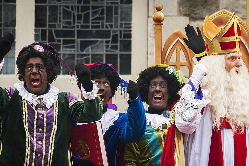 People dressed as Saint Nicolas (right) and "Black Peter" gesture during celebrations in Gouda, The Netherlands, on Nov 15, 2014.&nbsp;Dutch police on Saturday arrested 90 people protesting for and against the controversial "Black Pete" figure at the