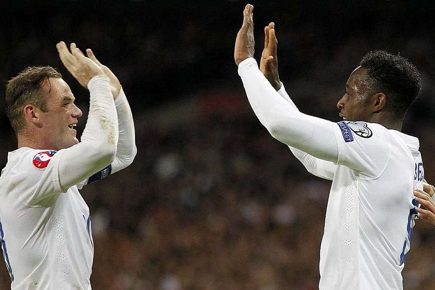 England's striker Danny Welbeck (right) celebrates with England's striker Wayne Rooney after Welbeck scored his team's third goal during the Euro 2016 Qualifier, Group E football match between England and Slovenia at Wembley in north London on Nov 15