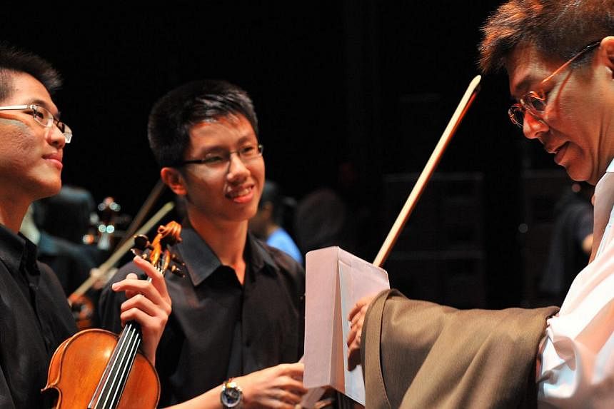 ChildAid artistic director Iskandar Ismail at the opening night in 2011 with two members of the combined schools orchestra at ChildAid 2009. -- PHOTO: ST FILE