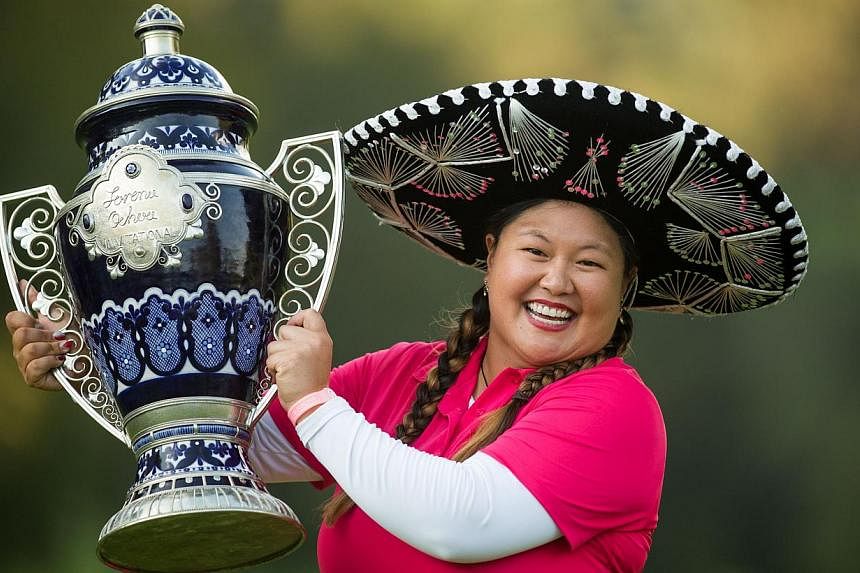 Christina Kim of the United States holds the champions trophy after her victory at the 2014 Lorena Ochoa Invitational presented by Banamex at Club de Golf Mexico in Mexico City on Nov 16, 2014. -- PHOTO: AFP&nbsp;