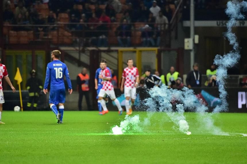 The game is interrupted as Croatia's supporters throw flares on the pitch during the Euro 2016 qualifying football match Italy vs Croatia at the San Siro stadium in Milan on Nov 16, 2014. -- PHOTO: AFP&nbsp;