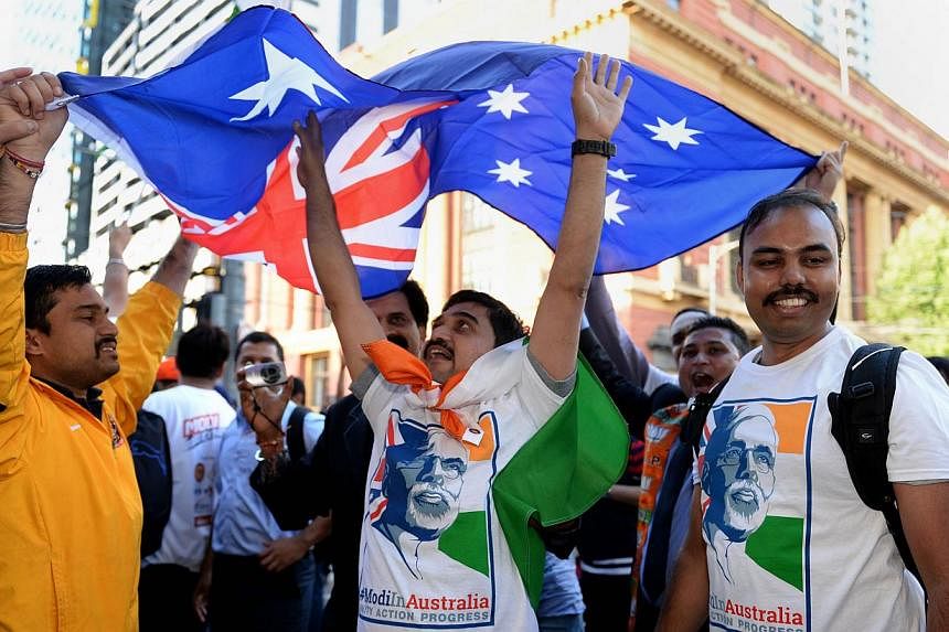 Supporters of India's Prime Minister Narendra Modi dance outside Southern Cross station in Melbourne while holding the Australian flag as they prepare to ride an overnight train with some 200 others to Sydney ahead of Modi's upcoming visit to that ci