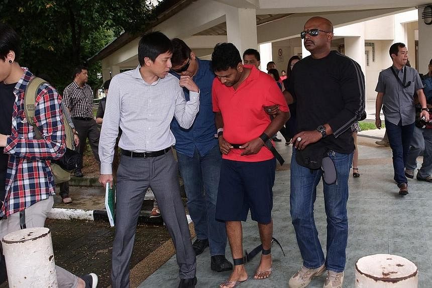 Annadurai Raman (in red), 42, one of the suspects who was charged in connection with the brazen robbery of a money changer in an open air carpark in early November is brought back to one of the crime scenes by the police at 3:15pm.&nbsp;A man suspect
