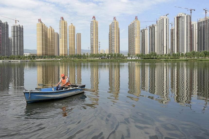 A man rowing a boat on a river in front of properties in Taiyuan, Shanxi province in this July 24, 2014 file photo. Average new home prices in China's 70 major cities fell 2.6 per cent in October from a year earlier, the second consecutive month show