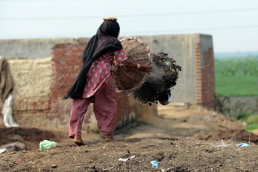 60 year old manual scavenger Kela collects human waste while cleaning a toilet in Nekpur village, Muradnagar in Uttar Pradesh, some 40 kms east of New Delhi. -- PHOTO: AFP