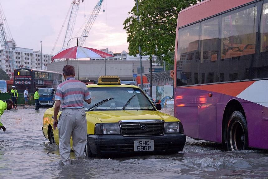 Heavy rain on the afternoon of Oct 20, 2013 left some vehicles like this taxi stranded in ankle-deep floodwaters in Ubi Avenue 2. -- PHOTO: ST FILE