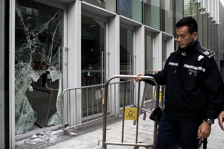 A policeman carries a barrier past a broken window of the government headquarters building in the Admiralty district of Hong Kong on Nov 19, 2014, after a small group attempted to break into the city's legislature. -- PHOTO: AFP