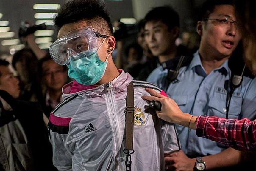 Police detain a man wearing protective as pro-democracy protesters faced-off with police outside the central government offices in the Admiralty district of Hong Kong on Nov 19, 2014. -- PHOTO: AFP