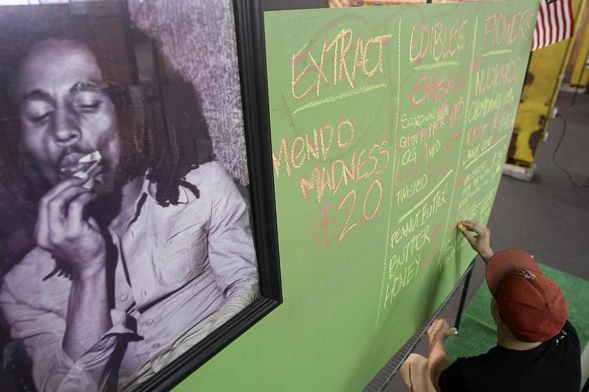 A portrait of reggae legend Bob Marley hangs next to a menu of marijuana products at the medical marijuana farmers market at the California Heritage Market in Los Angeles. His family and a Seattle-based private equity firm on Nov 18, 2014, said they 
