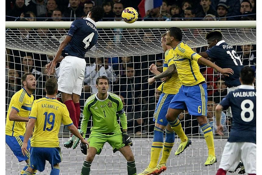 French defender Raphael Varane (left) jumps for the ball during the friendly football match France vs Sweden at the Velodrome stadium in Marseille, southern France on Nov 18, 2014. -- PHOTO: AFP&nbsp;