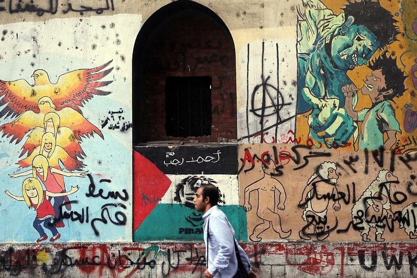 A man walks past graffiti denouncing the Interior and Defence Ministry and members of the Muslim Brotherhood, along Mohamed Mahmoud Street, during the third anniversary of violent and deadly clashes near Tahrir Square in Cairo on Nov 19, 2014.&nbsp;-