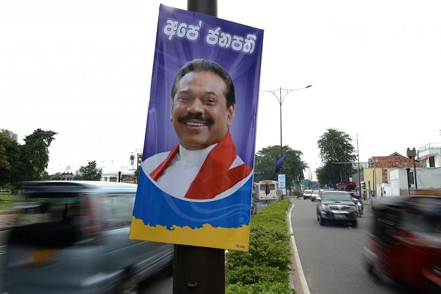 Sri Lankan motorists travel past a poster of President Mahinda Rajapakse in Colombo on Nov 19, 2014.&nbsp;Sri Lanka President Mahinda Rajapakse confirmed Thursday he would seek a third term in office, with snap elections expected in January. -- PHOTO