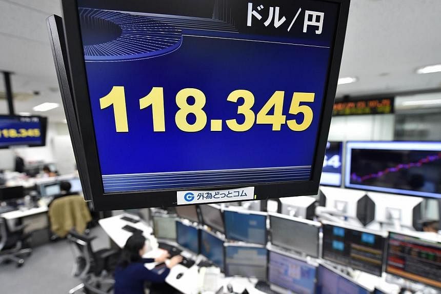 A foreign exchange rate board (upper) is displayed at a foreign exchange brokerage in Tokyo on Nov 20, 2014.&nbsp;The Japanese currency is sinking. -- PHOTO: AFP