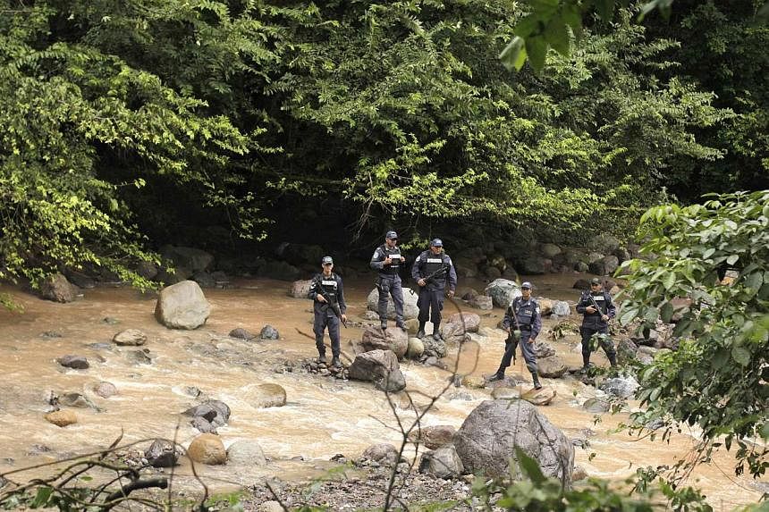 Police officers stand guard near a crime scene in Arada on Nov 19, 2014. The bodies of Maria Jose Alvarado, 19, and her sister Sofia, 23, were found buried near a river in the mountainous region of Santa Barbara in western Honduras. -- PHOTO: REUTERS