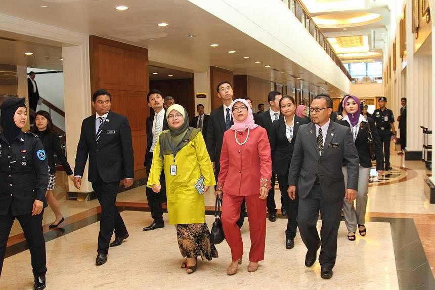 Madam Halimah (in red) flanked by Malaysian officials in a corridor of the Malaysian Parliament in Kuala Lumpur, on Wednesday. -- PHOTO: SINGAPORE PARLIAMENT HOUSE