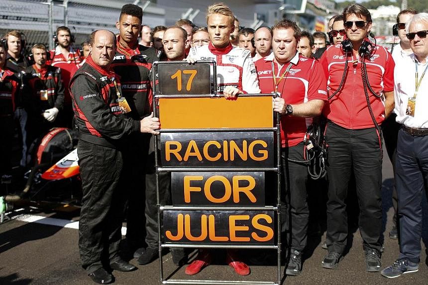 Marussia Formula One driver Max Chilton (centre) and his team members pray for driver Jules Bianchi who had accident in the previous race, before the first Russian Grand Prix in Sochi on Oct 12, 2014. The Marussia Formula One team has failed in a lat
